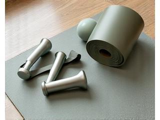 Attrezzi fitness minimalistici come fasce di resistenza, pesi leggeri e tappetino yoga.